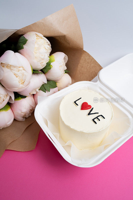便当蛋糕，上面写着"爱与心"还有一束花。一个可爱的甜点礼物，适合任何场合给你爱的人。贺卡。爱情与糖果概念